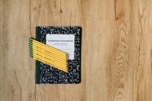 An image depicting a notebook with ten pencils neatly placed on the notebook